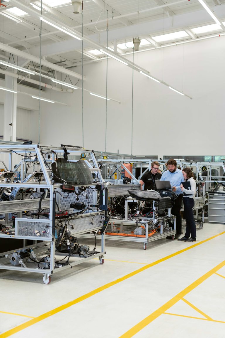 Ingenieurteam inspiziert Maschinen in einer modernen Produktionshalle für Automatisierungstechnik.