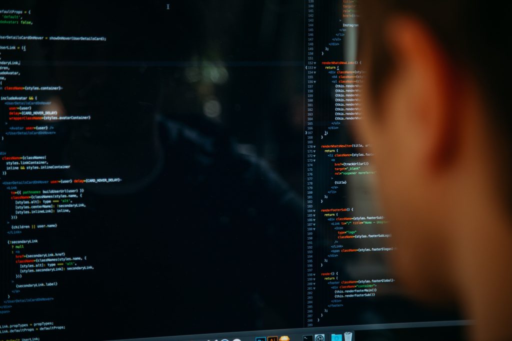 Entwickler programmiert am Computerbildschirm, Quellcode für Automatisierungstechnik wird angezeigt.